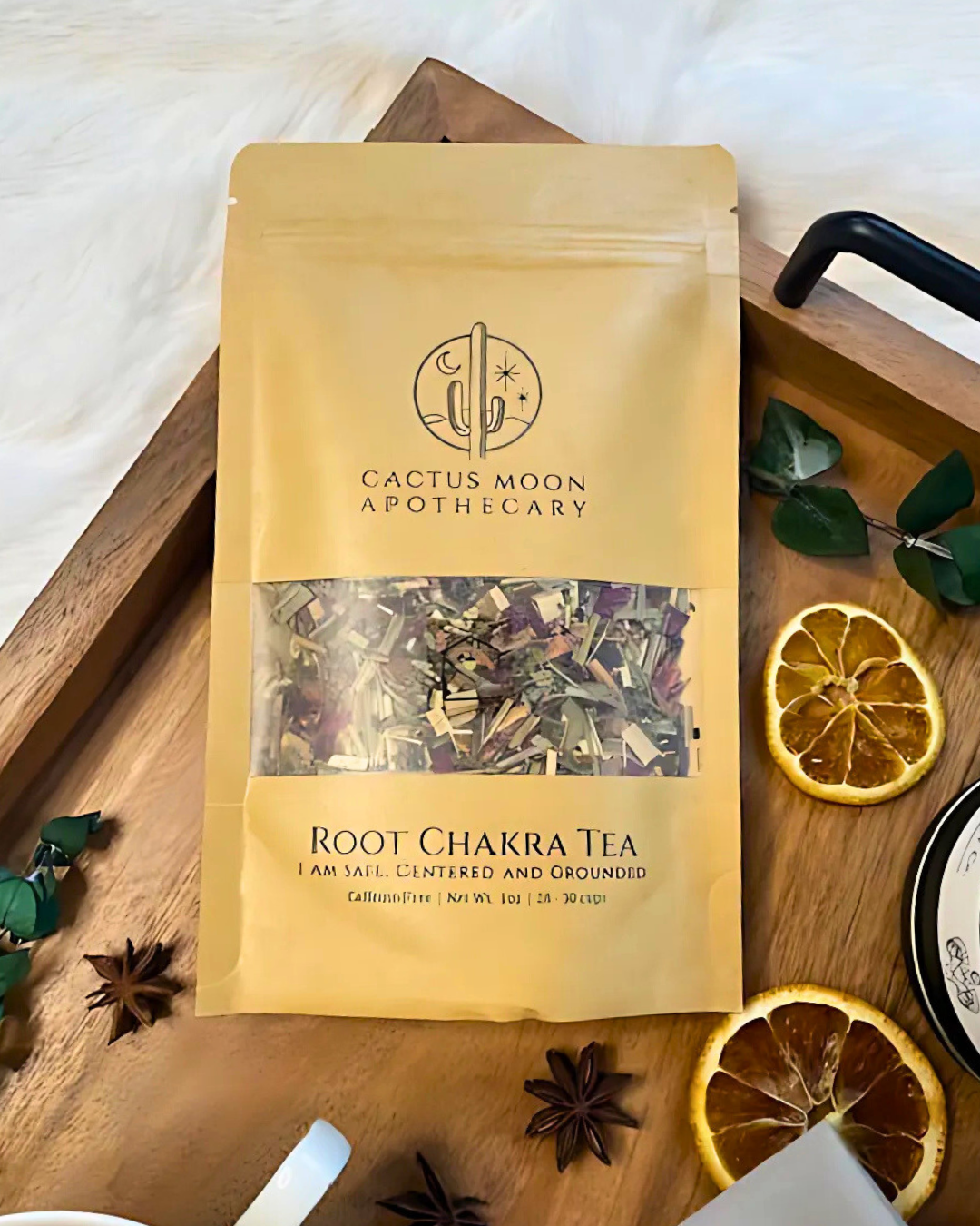Cactus Moon Apothecary Root Chakra Tea package on a wooden tray with dried oranges and star anise.