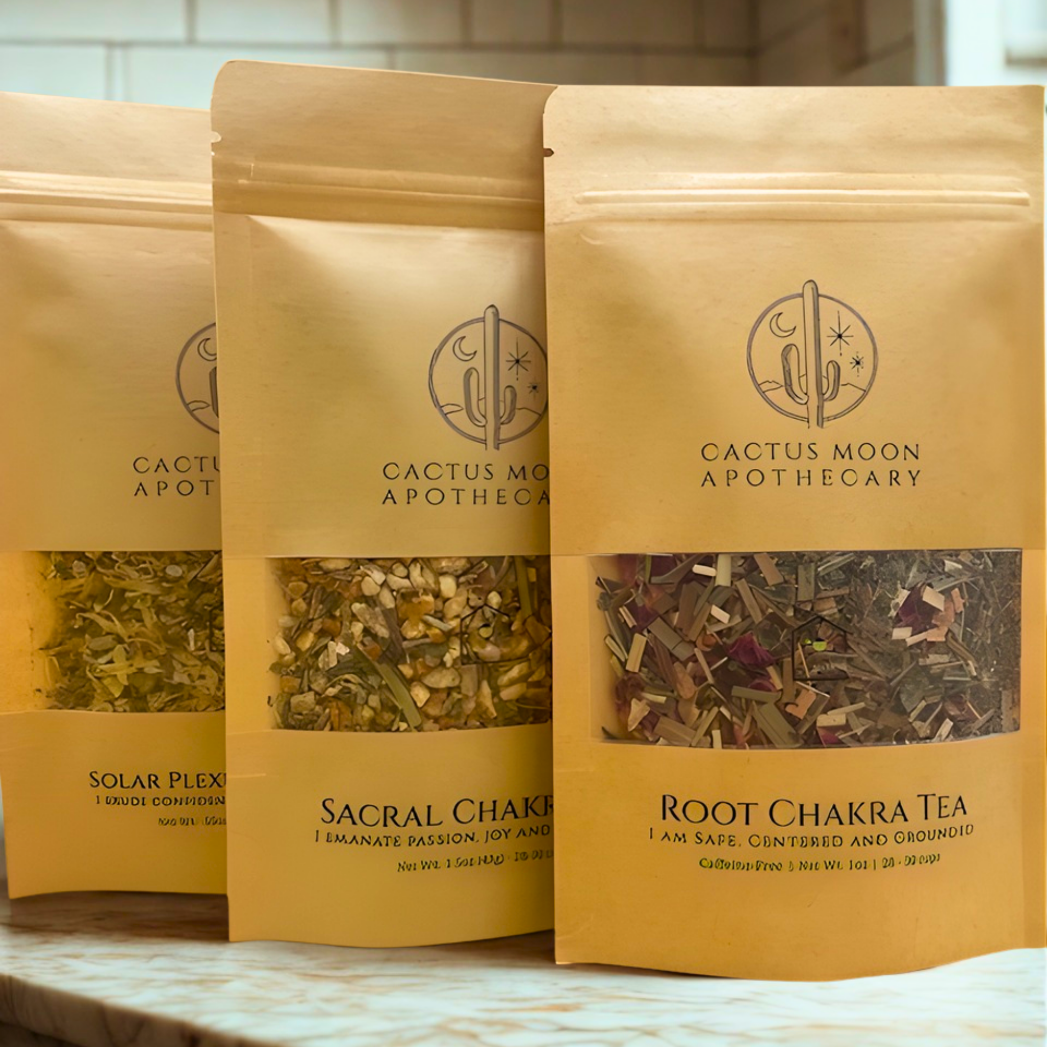 Three packages of Cactus Moon Apothecary tea on a marble surface.