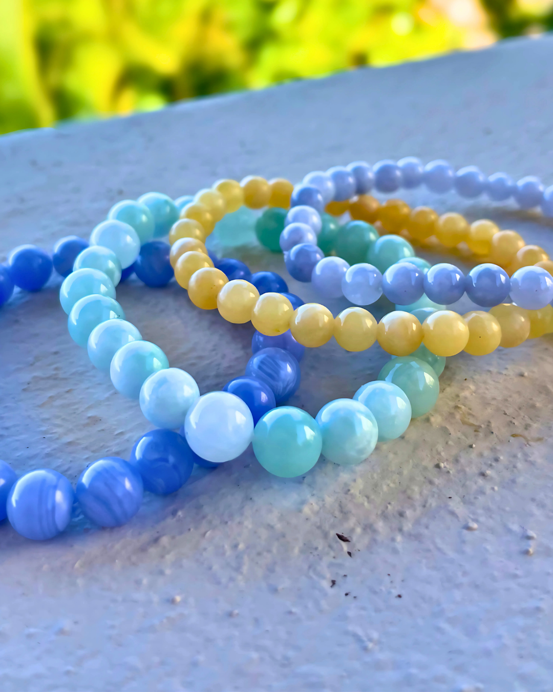 Set of colorful beaded bracelets on a light surface with a blurred natural background