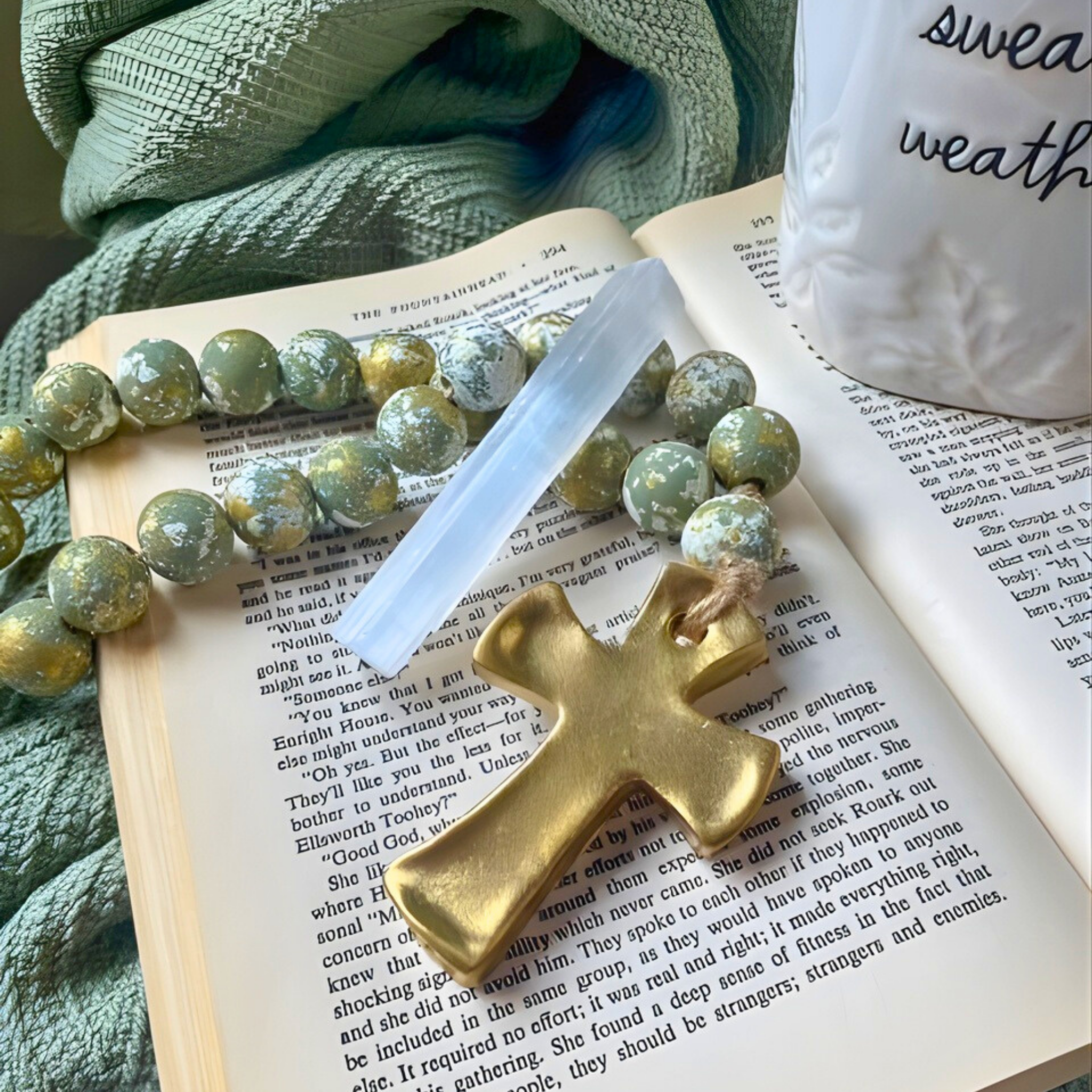 Gold cross charm on a book with green beads