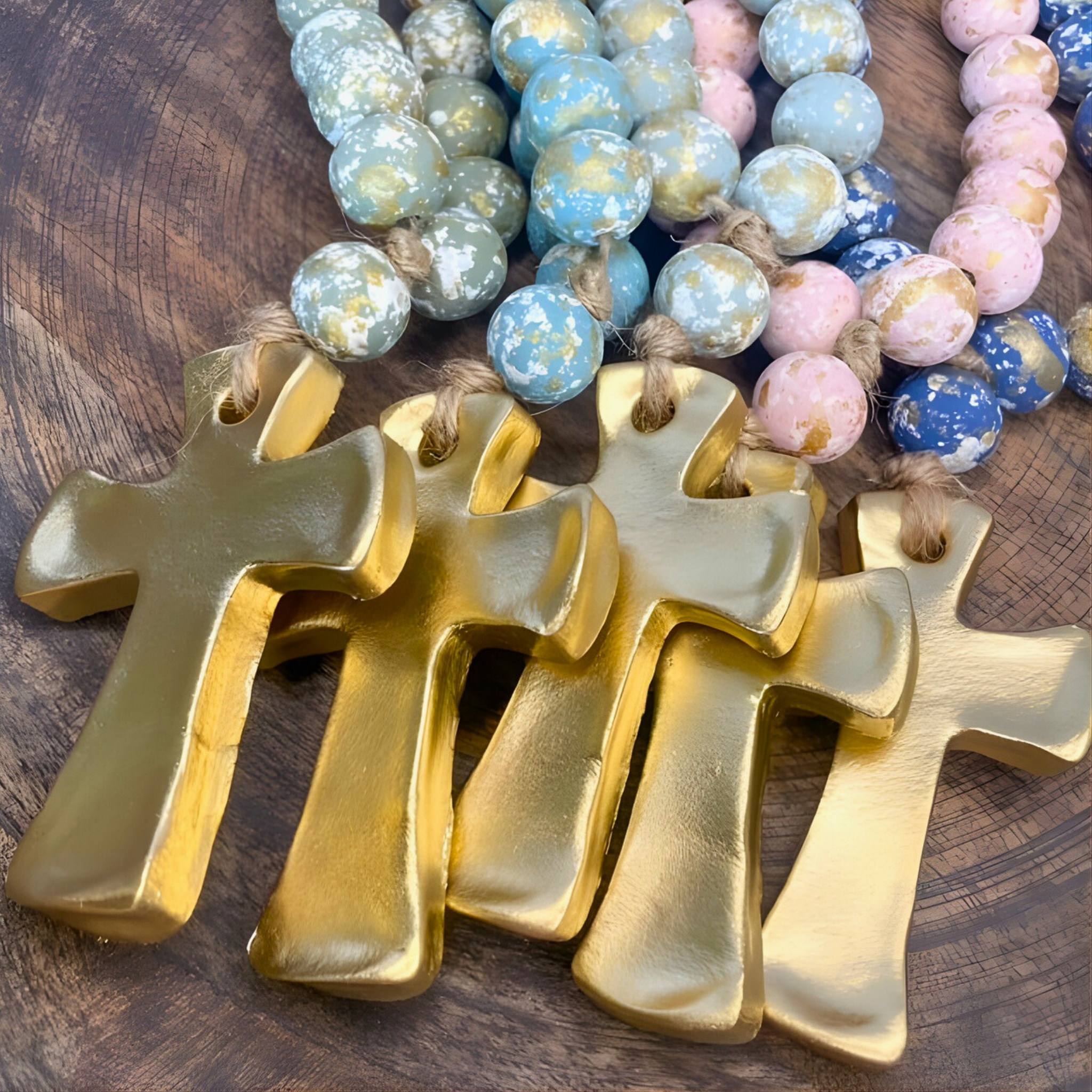Gold crosses on a wooden surface with colorful beaded necklaces in the background