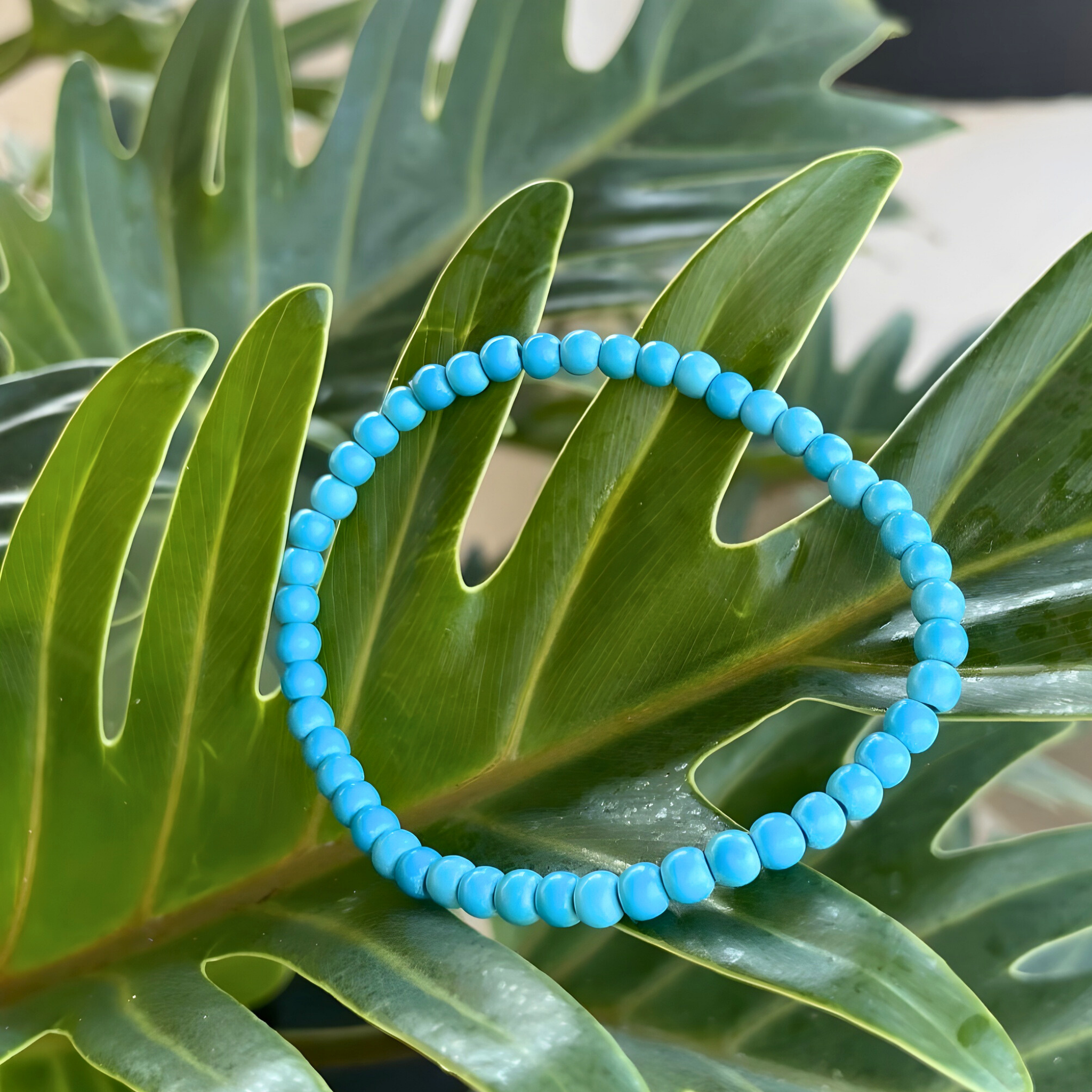 Blue beaded bracelet on a green leaf