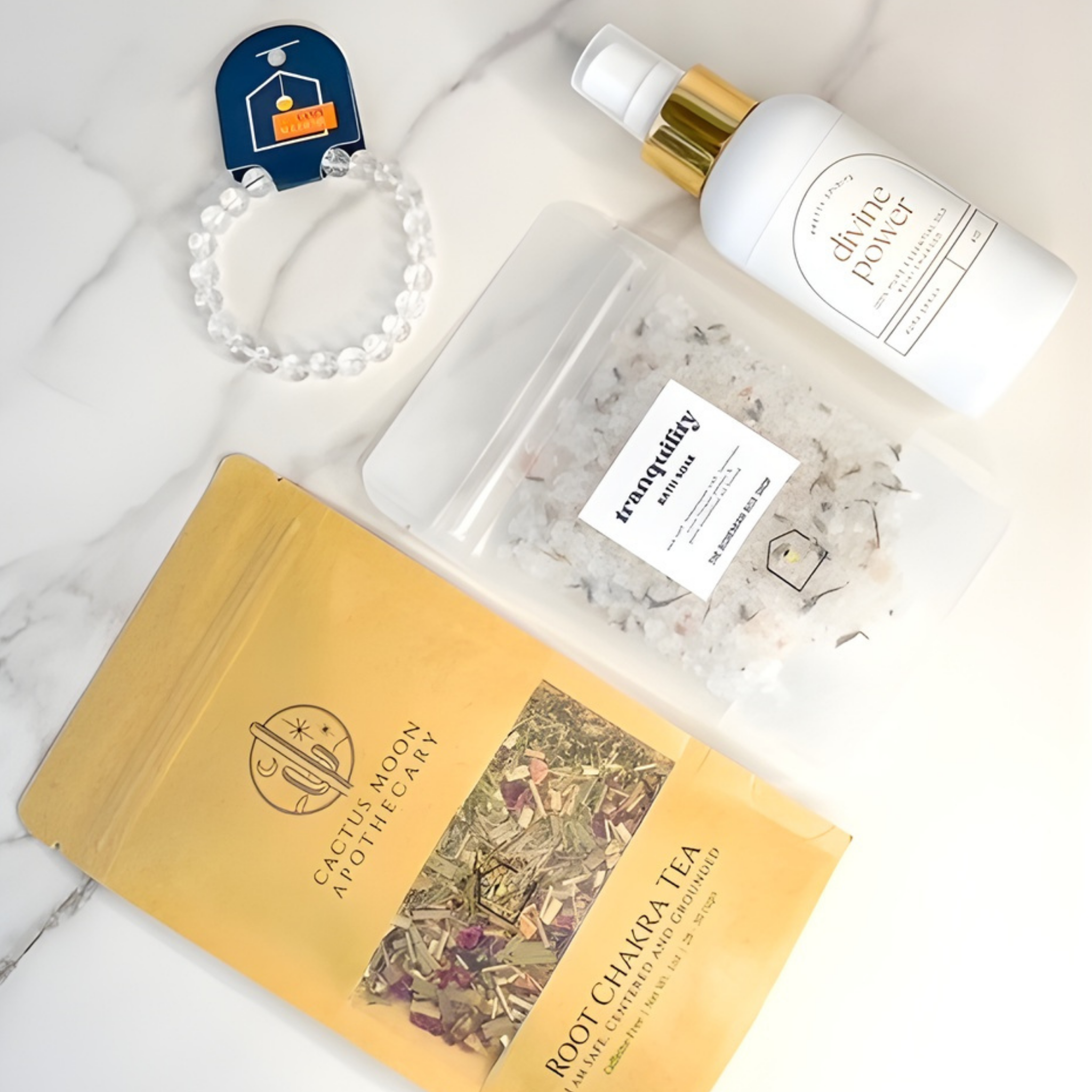 Collection of wellness products including a bottle, a bag of tea, and a bracelet on a marble surface.