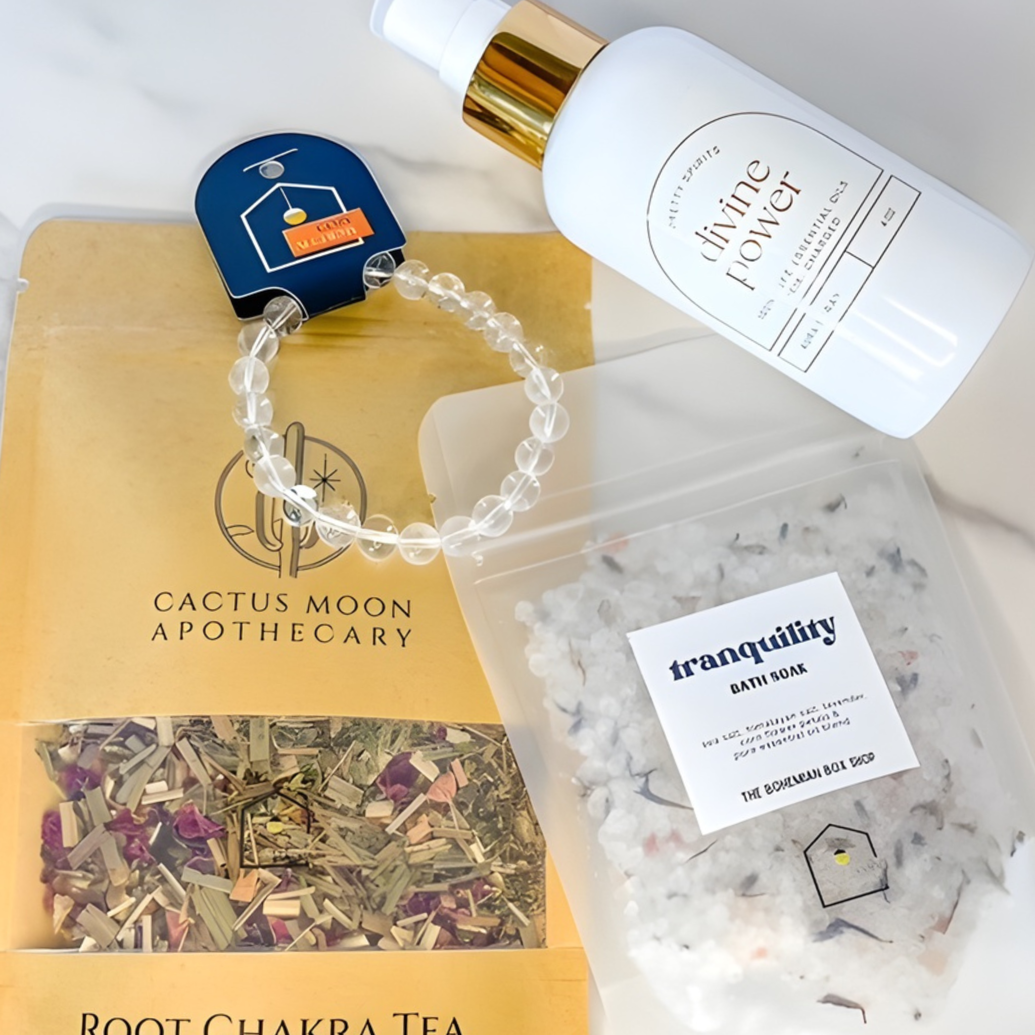 Collection of wellness products including a bracelet, tea, bath salts, and a bottle with 'Cactus Moon Apothecary' branding.