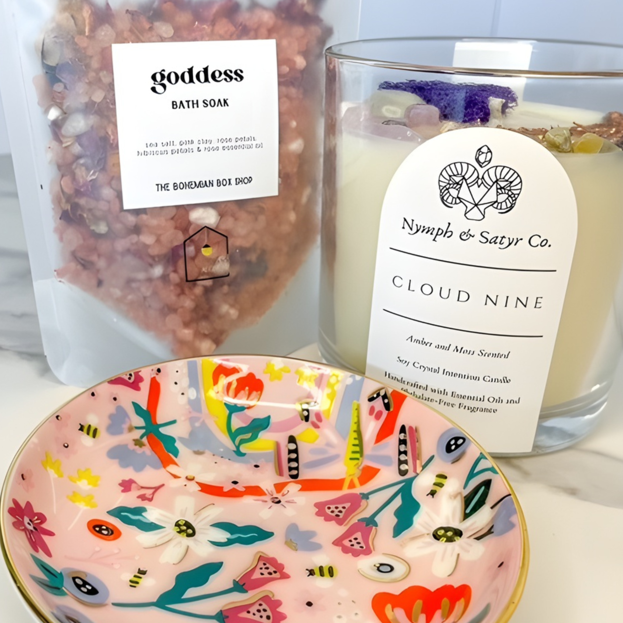 Bath soak, candle, and decorative bowl on a surface with visible branding.