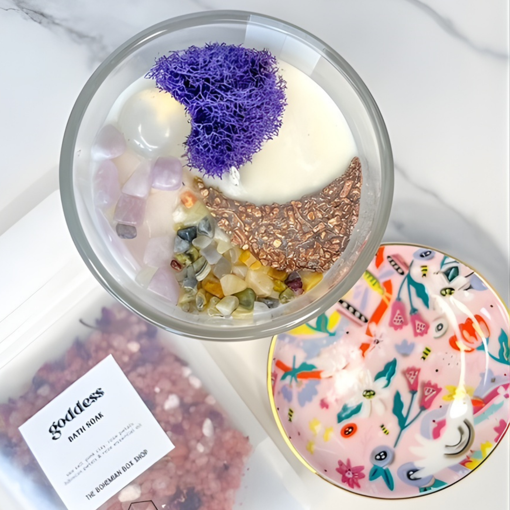 Glass container with bath bomb and decorative elements on a marble surface