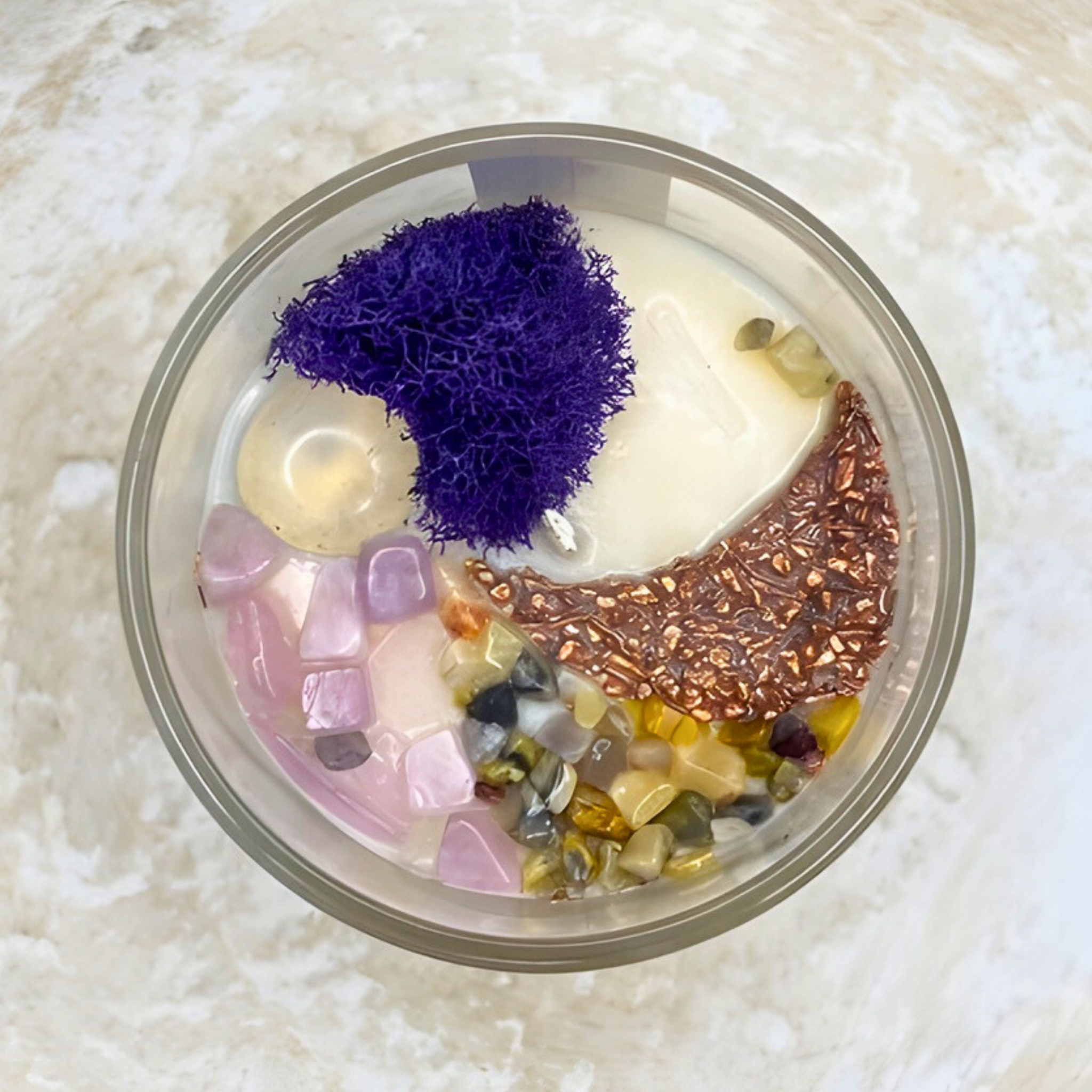 Colorful stones and crystals in a glass container on a textured white background