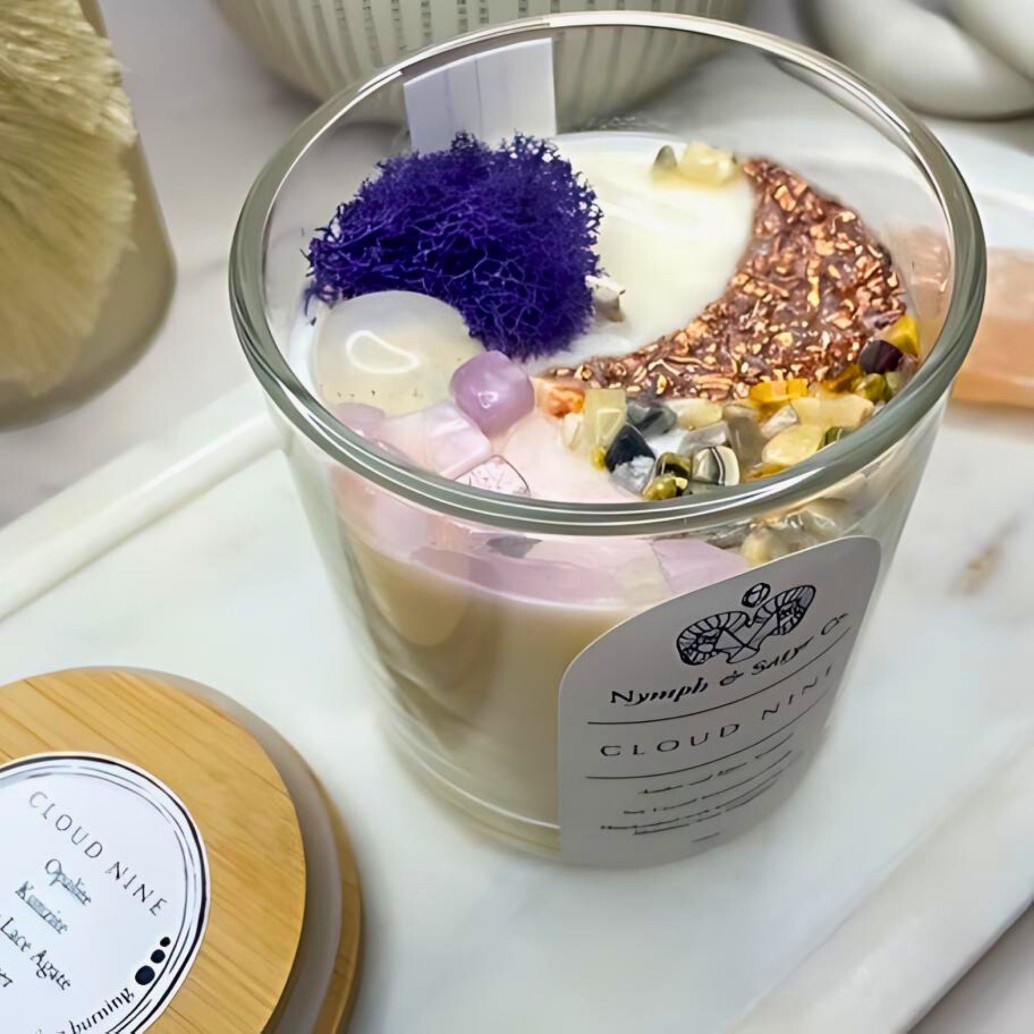 Glass candle with decorative elements and a label on a white surface