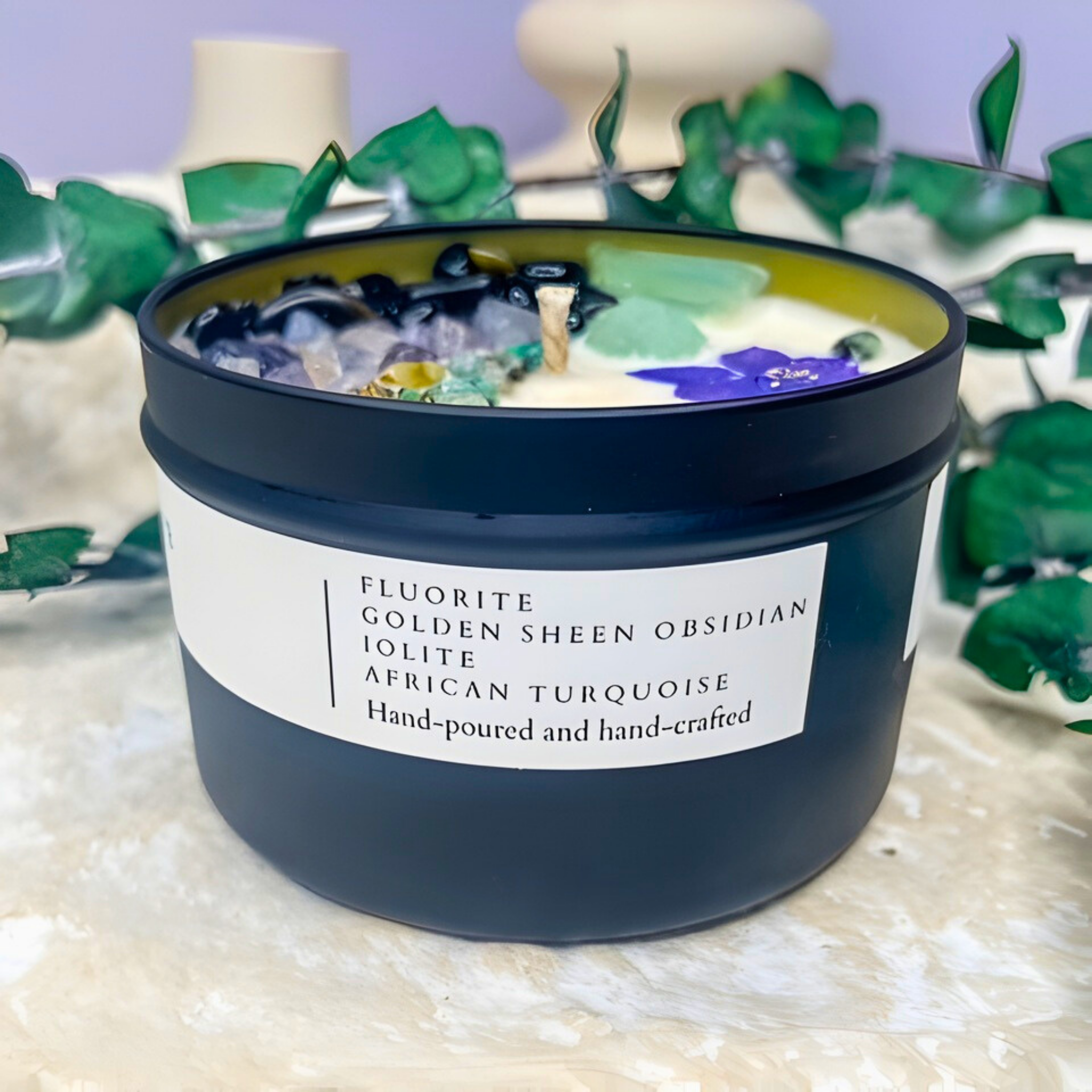 Candle in a black container with a label on a textured surface