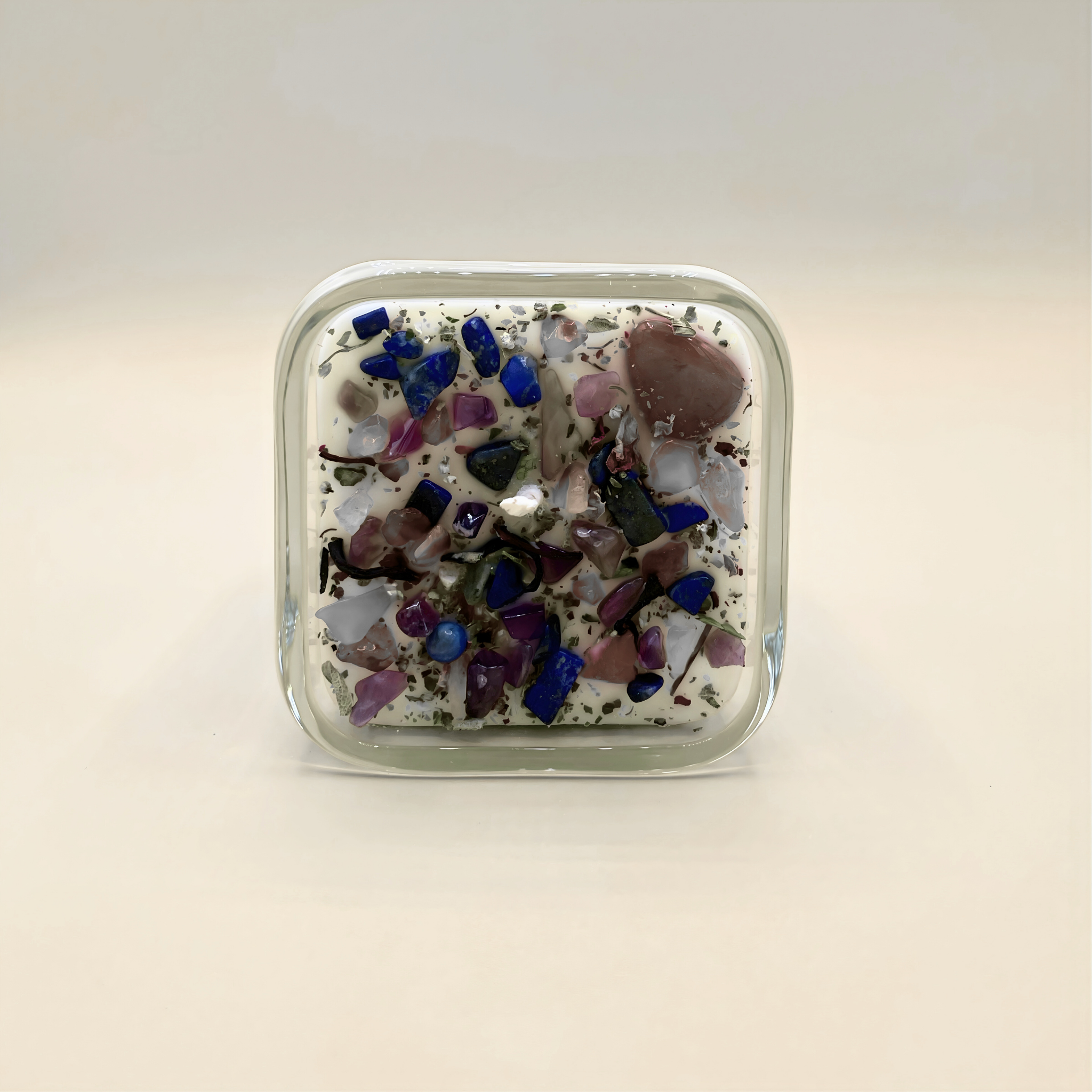 Square glass container with multicolored stones on a light beige background
