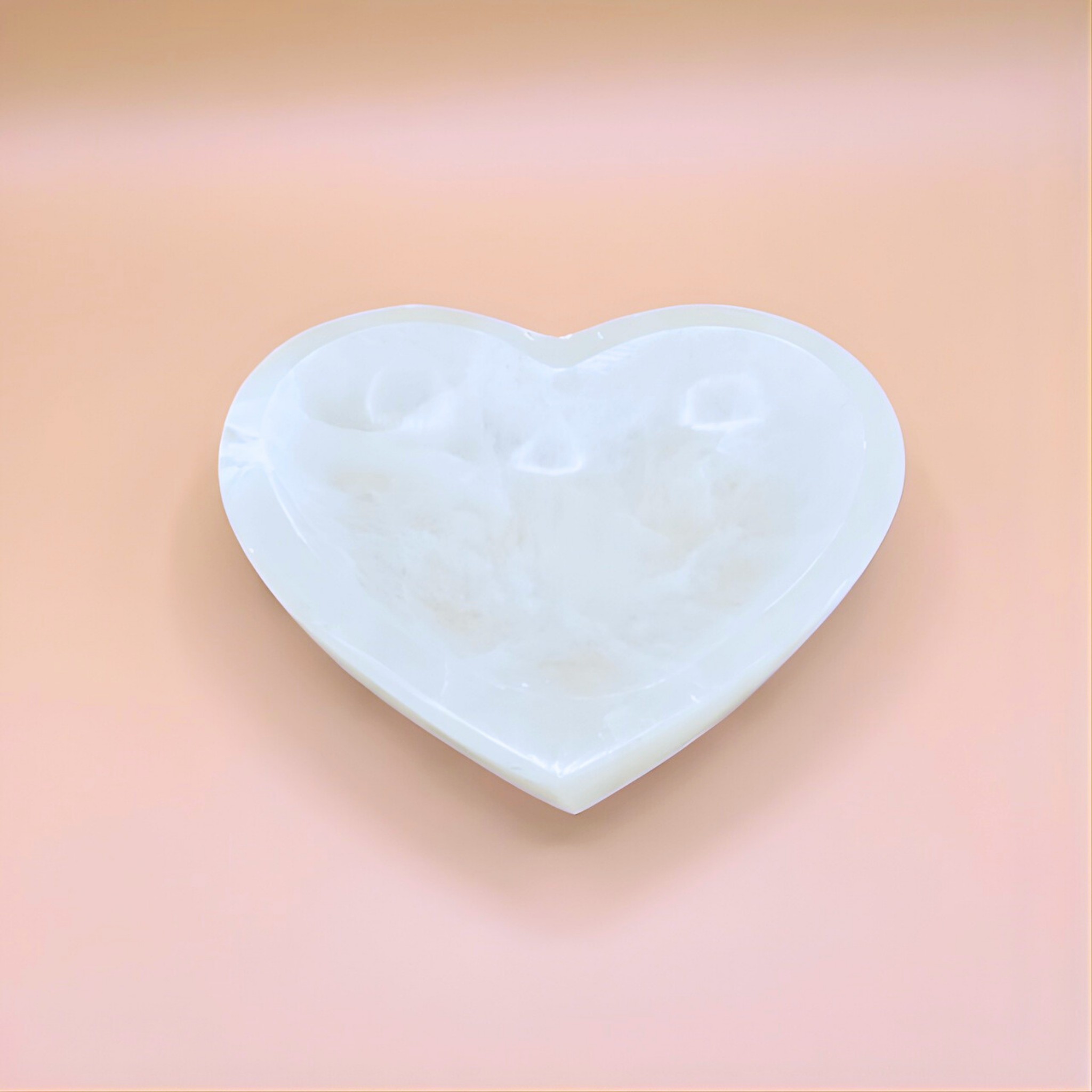 Heart-shaped white stone on a pink background