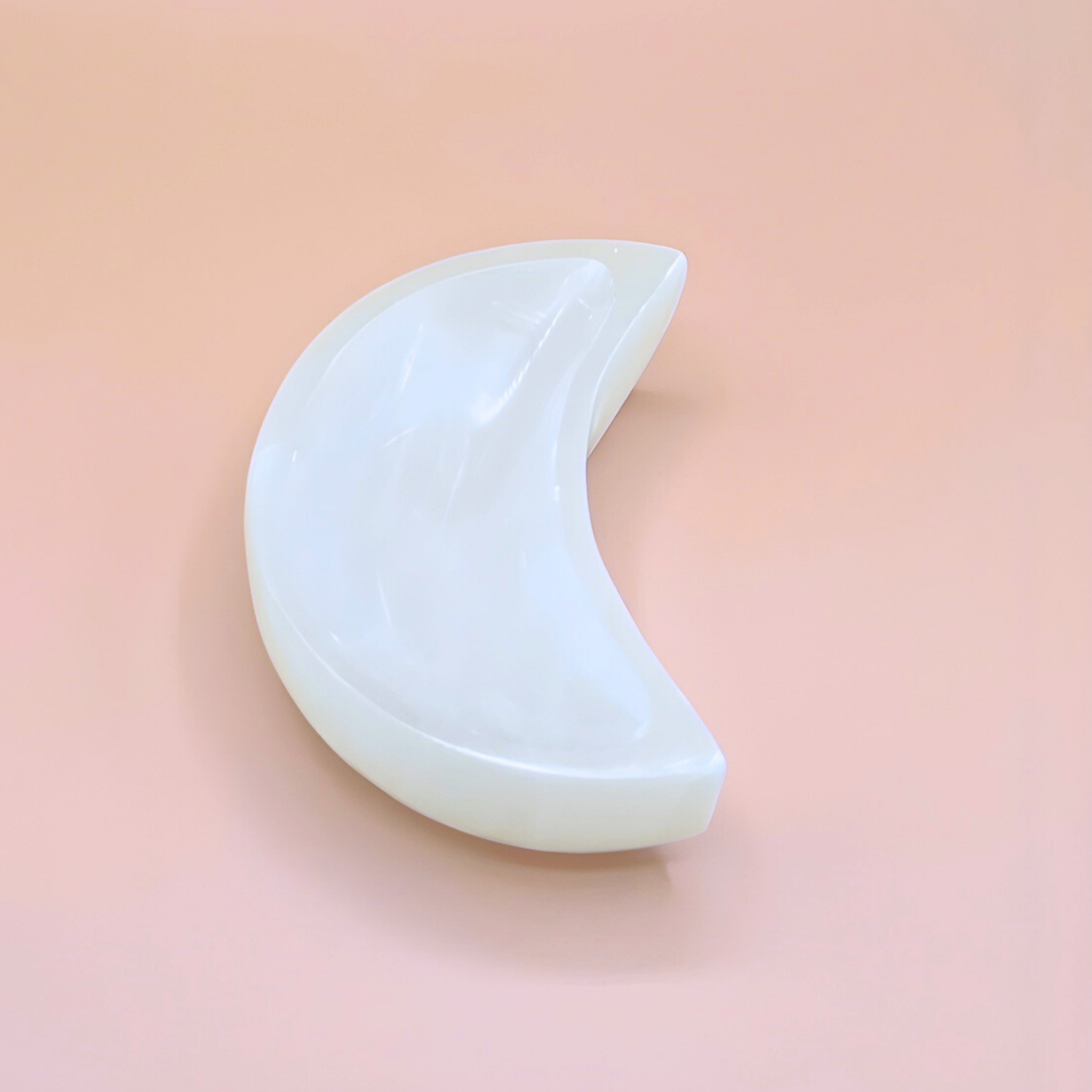 White crescent-shaped object on a pink background