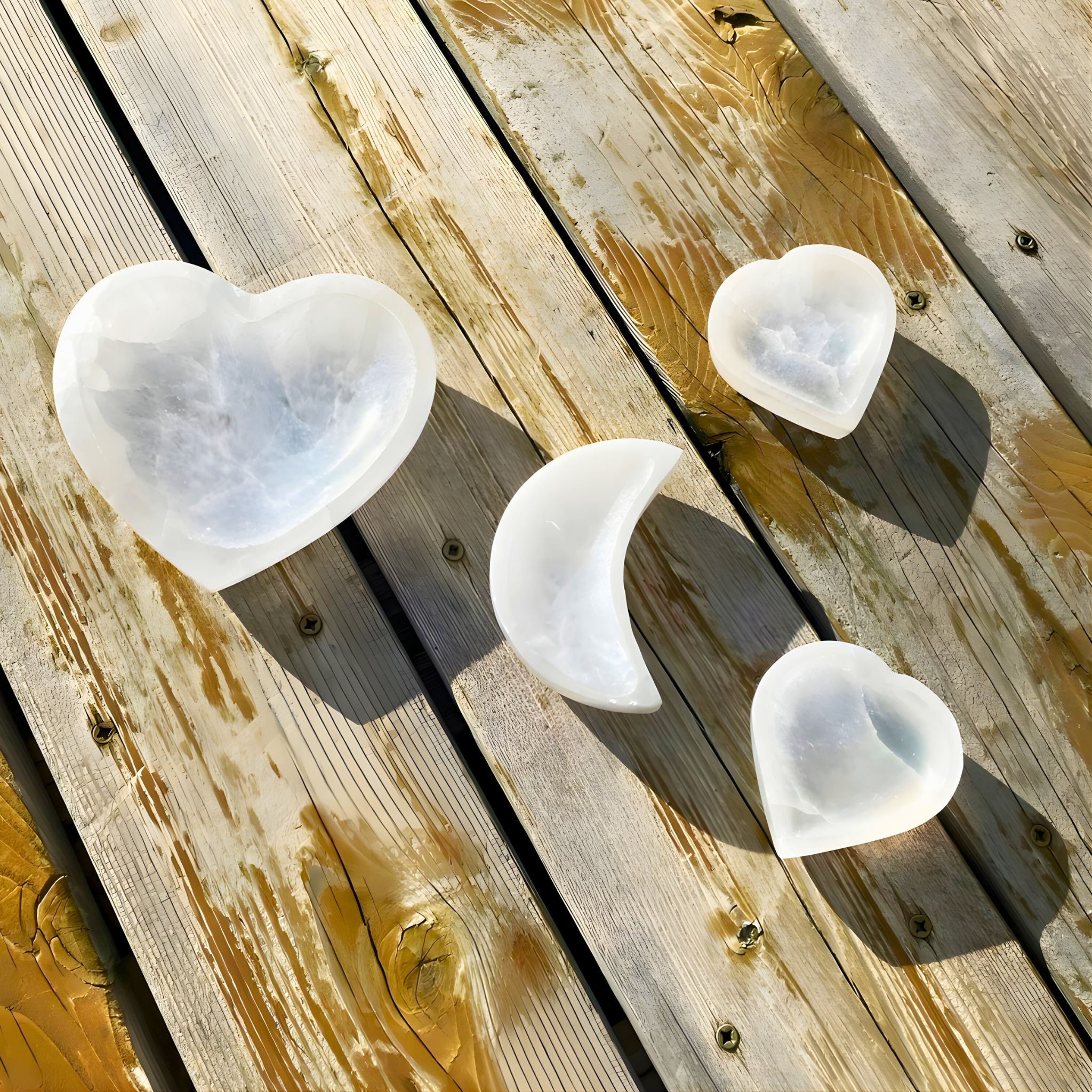 Heart-shaped and crescent moon-shaped white stones on a wooden surface