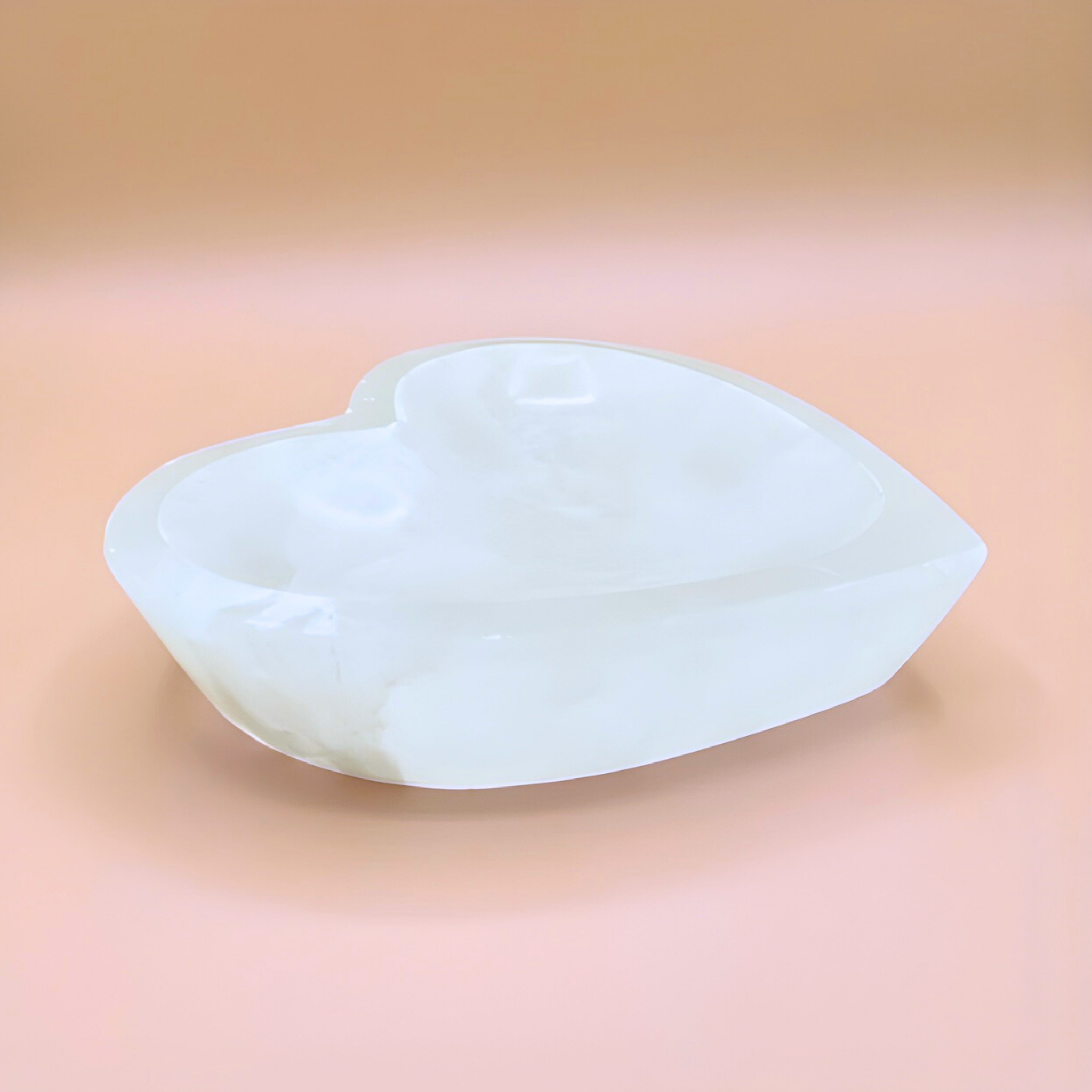 Heart-shaped white stone on a pink background