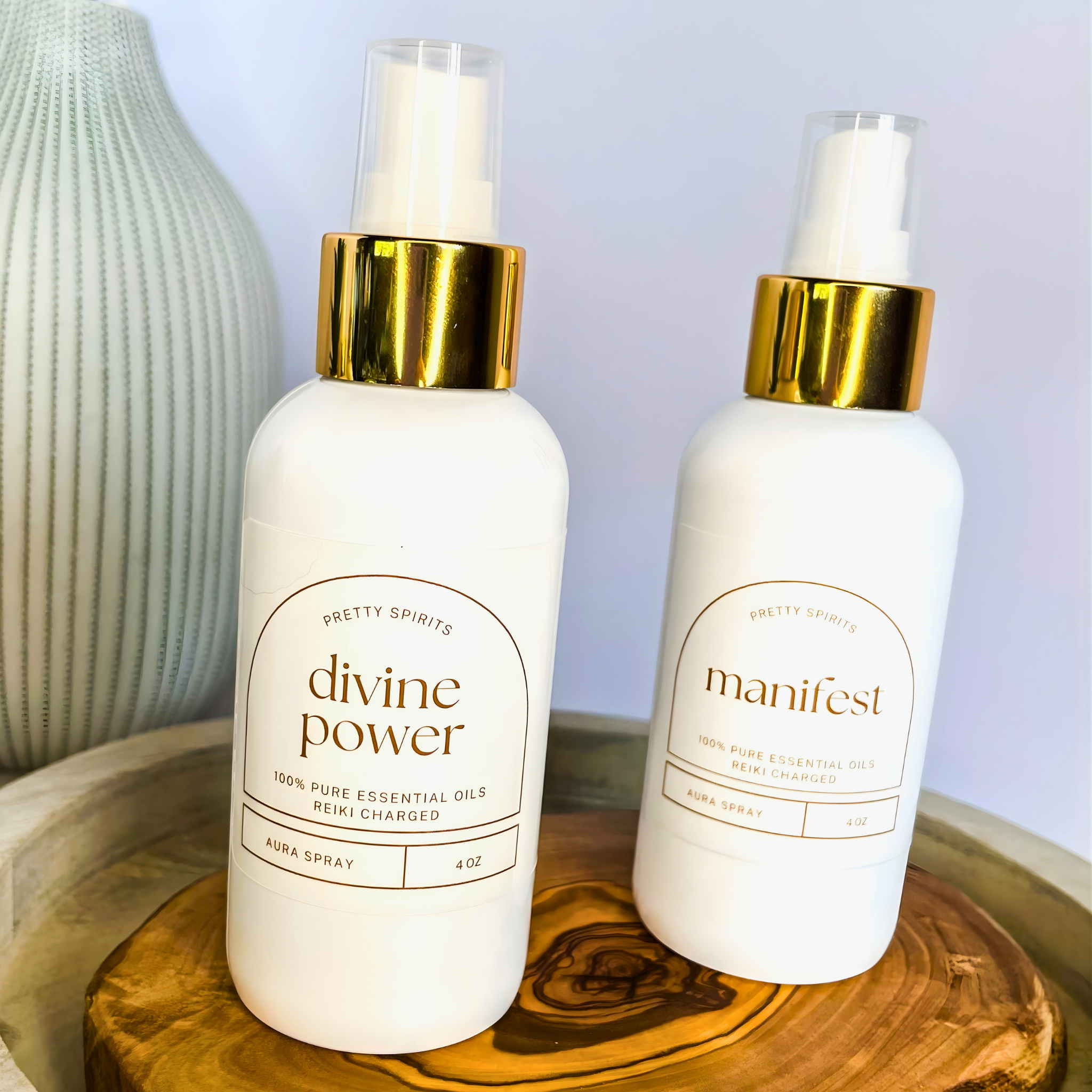Two white bottles with gold caps labeled 'divine power' and 'manifest' on a wooden surface.