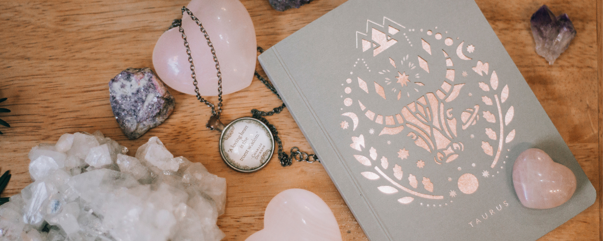 Necklace with heart pendant on a wooden surface with crystals and a card featuring a unicorn design.