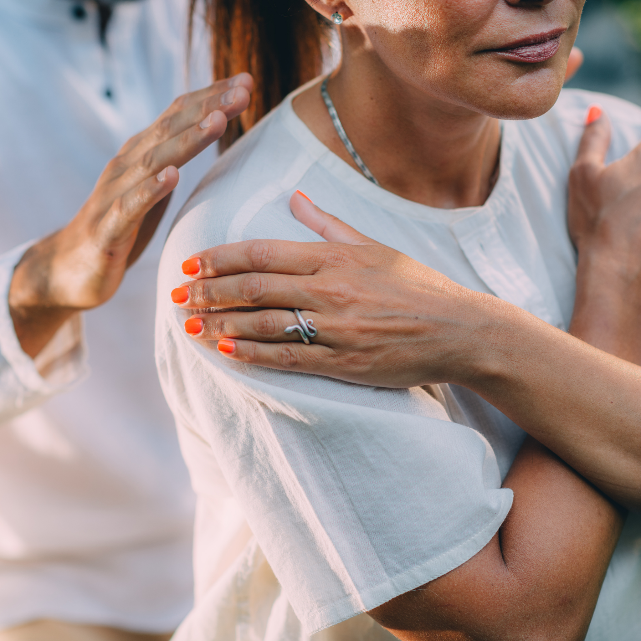 Woman wearing a white dress with another person's hand on her shoulder