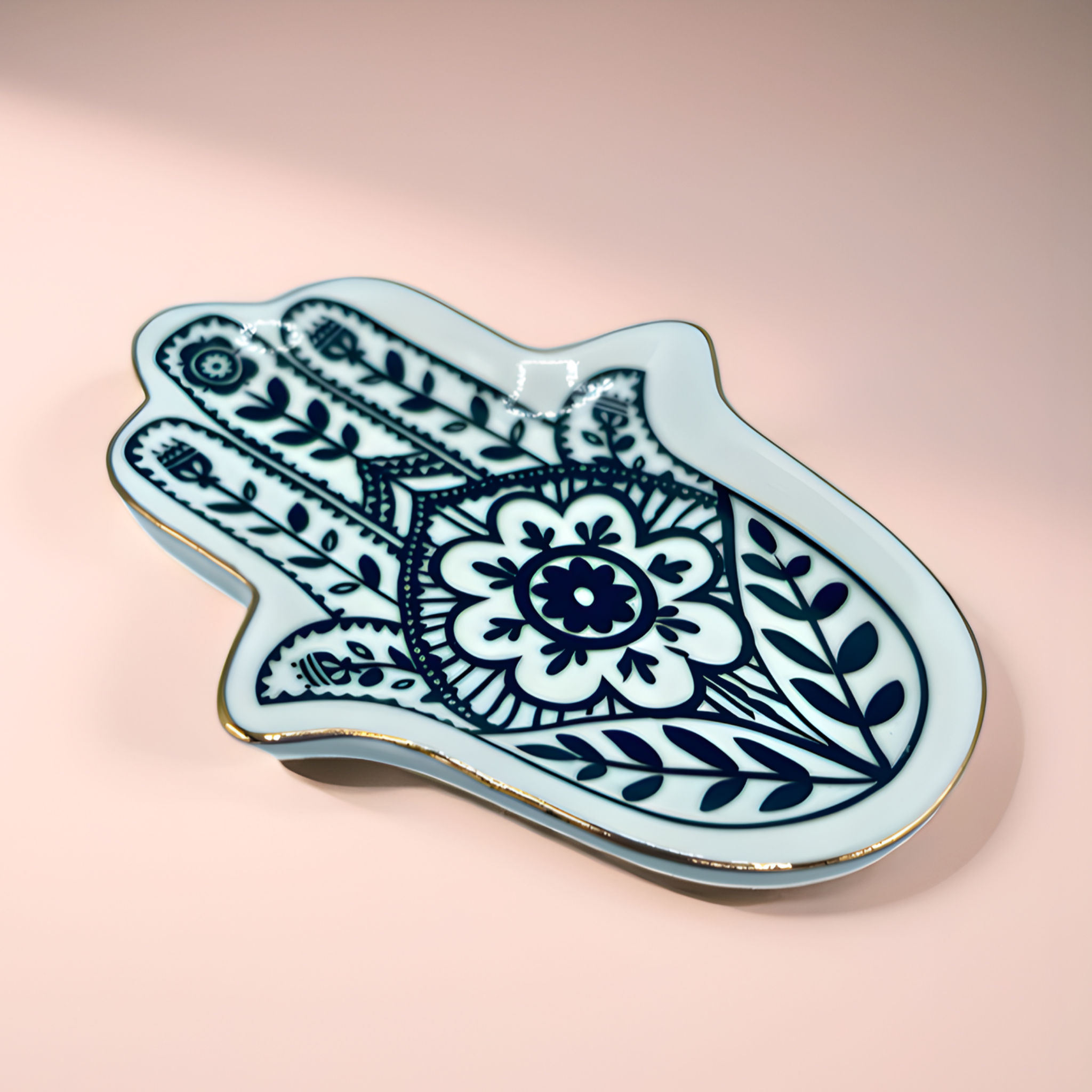 Decorative Hamsa-shaped plate with blue floral patterns on a pink background