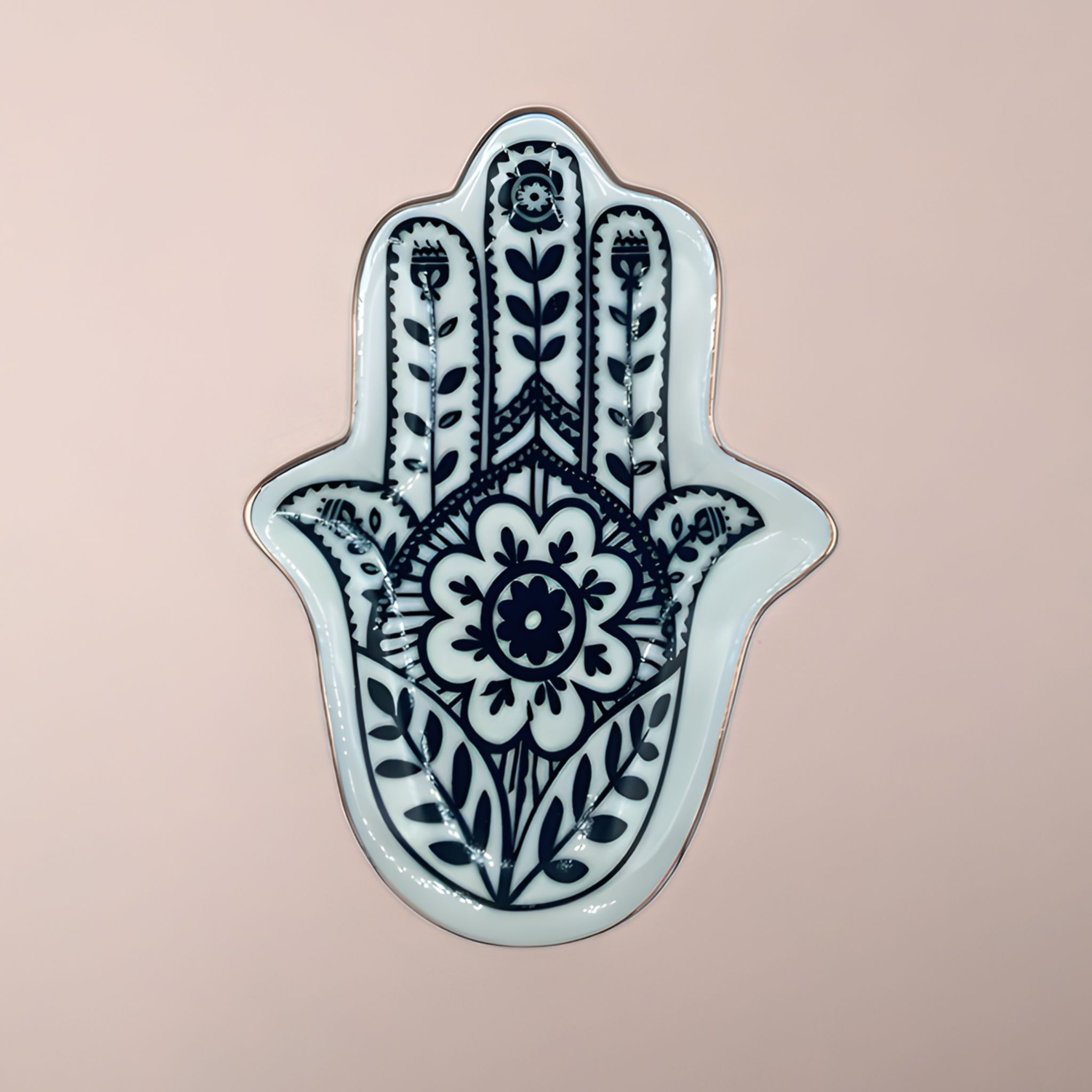 Decorative Hamsa hand with intricate black patterns on a light pink background