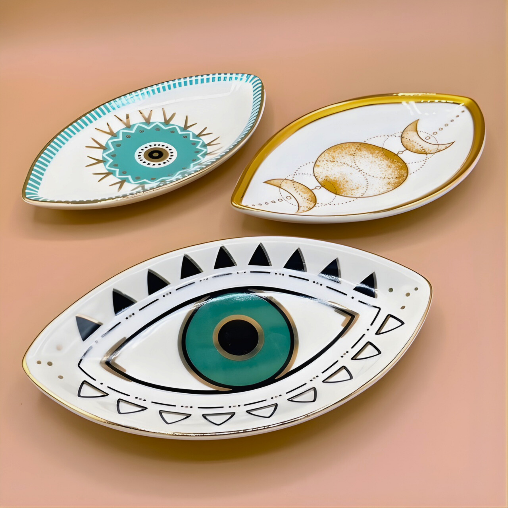 Three decorative ceramic plates with eye designs on a beige background