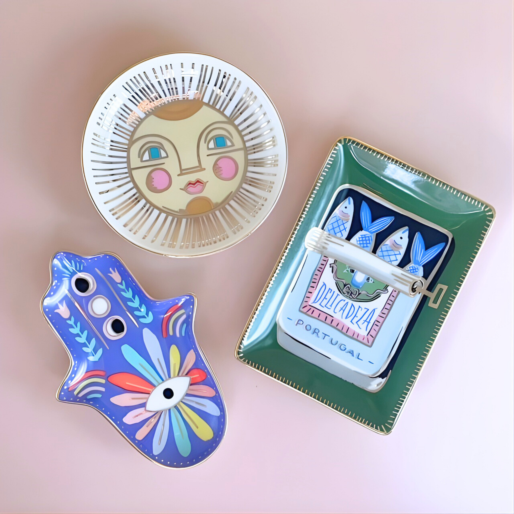 Colorful decorative items including a small mirror, a blue hand-shaped object, and a green box with fish design on a pink background.
