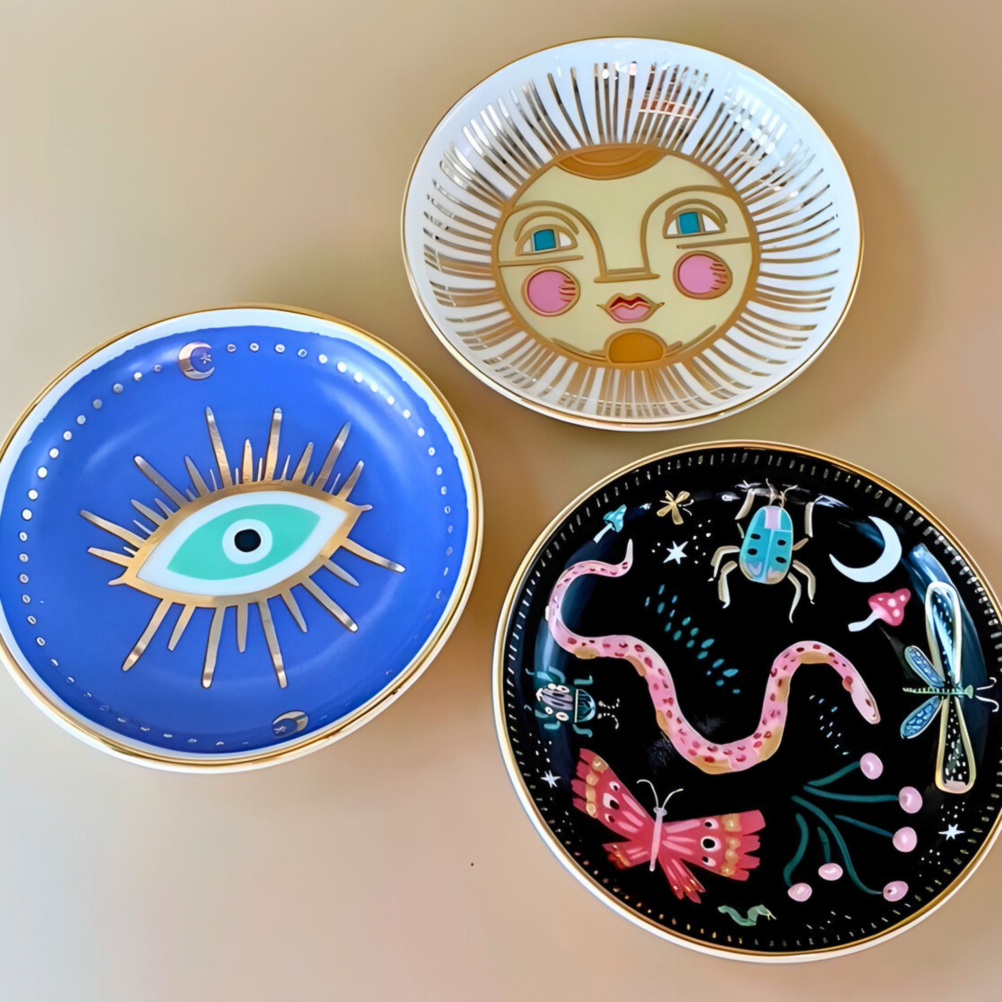 Three decorative plates with artistic designs on a beige background