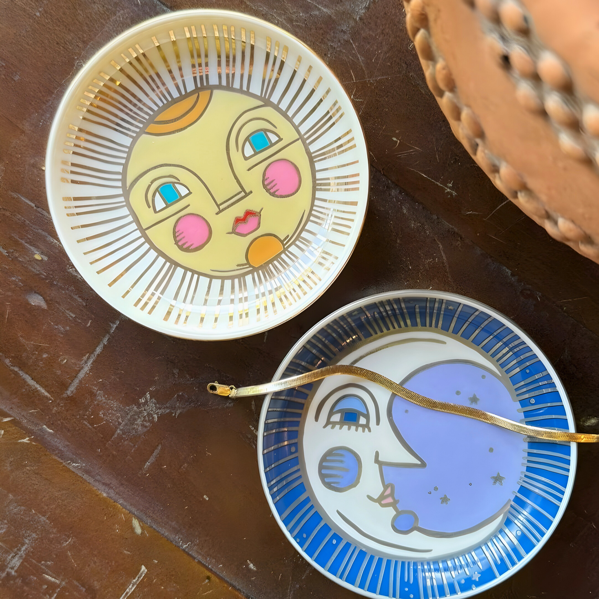 Two decorative plates with face designs on a wooden surface
