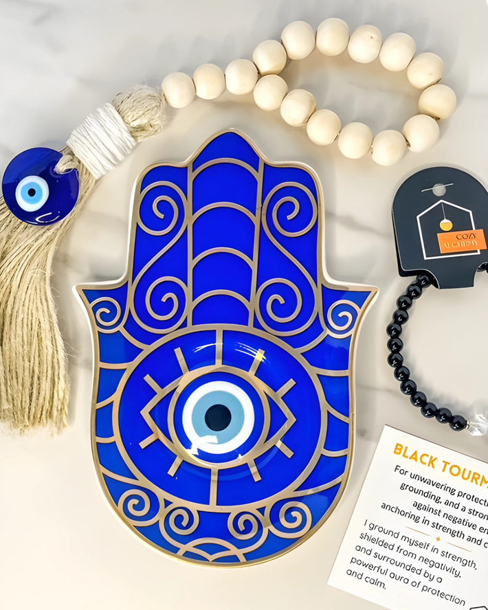 Blue Hamsa hand with evil eye design, tassel, and prayer beads on a white background