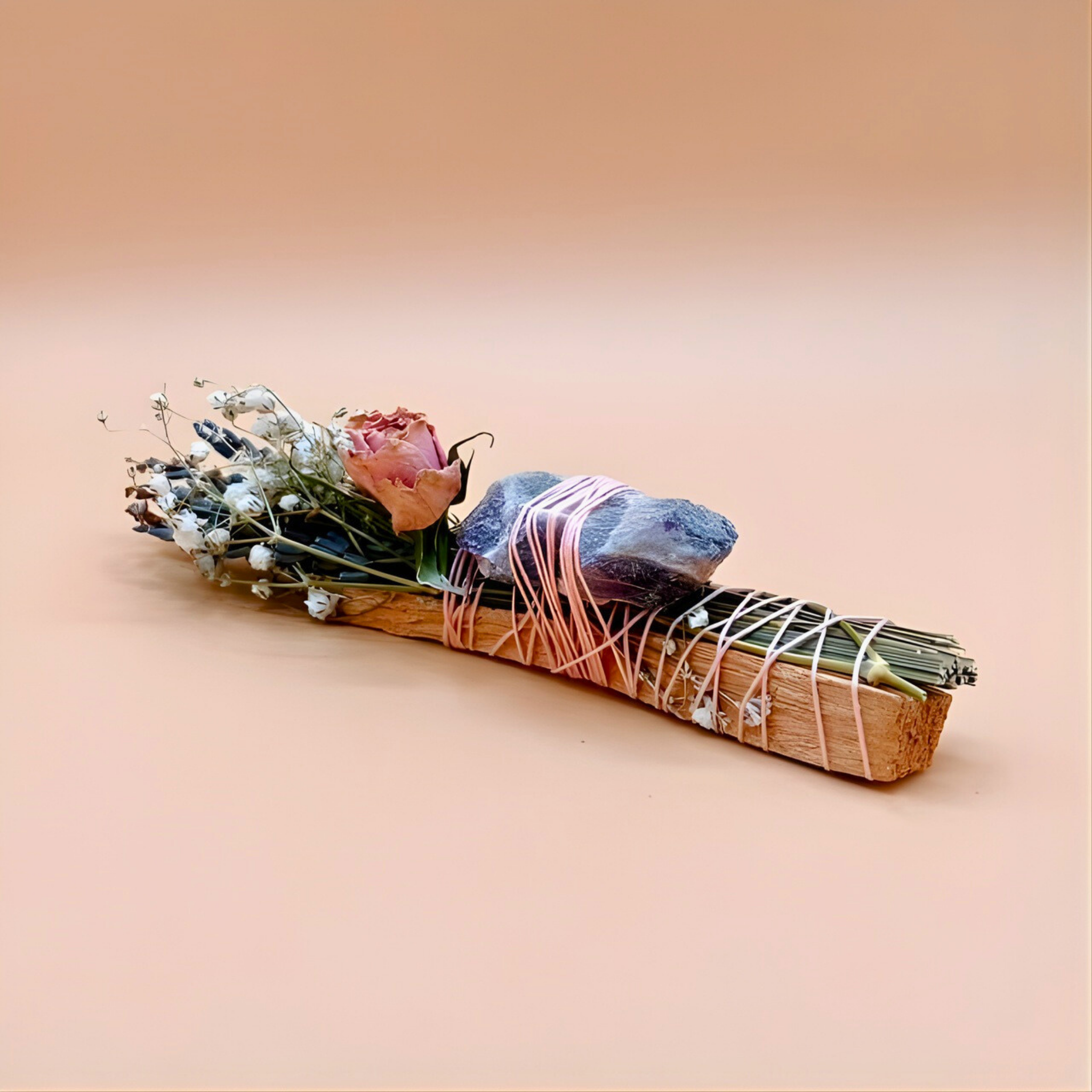Smudging stick with flowers and stones on a beige background