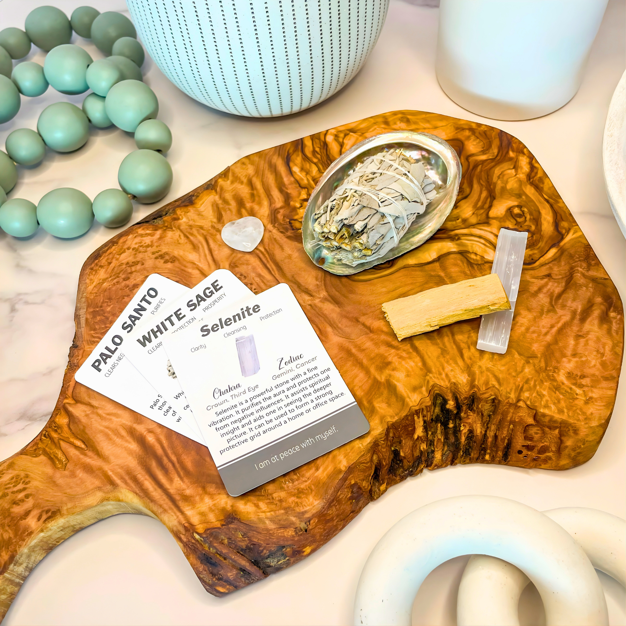 Wooden tray with Palo Santo, White Sage, and Selenite on a marble surface