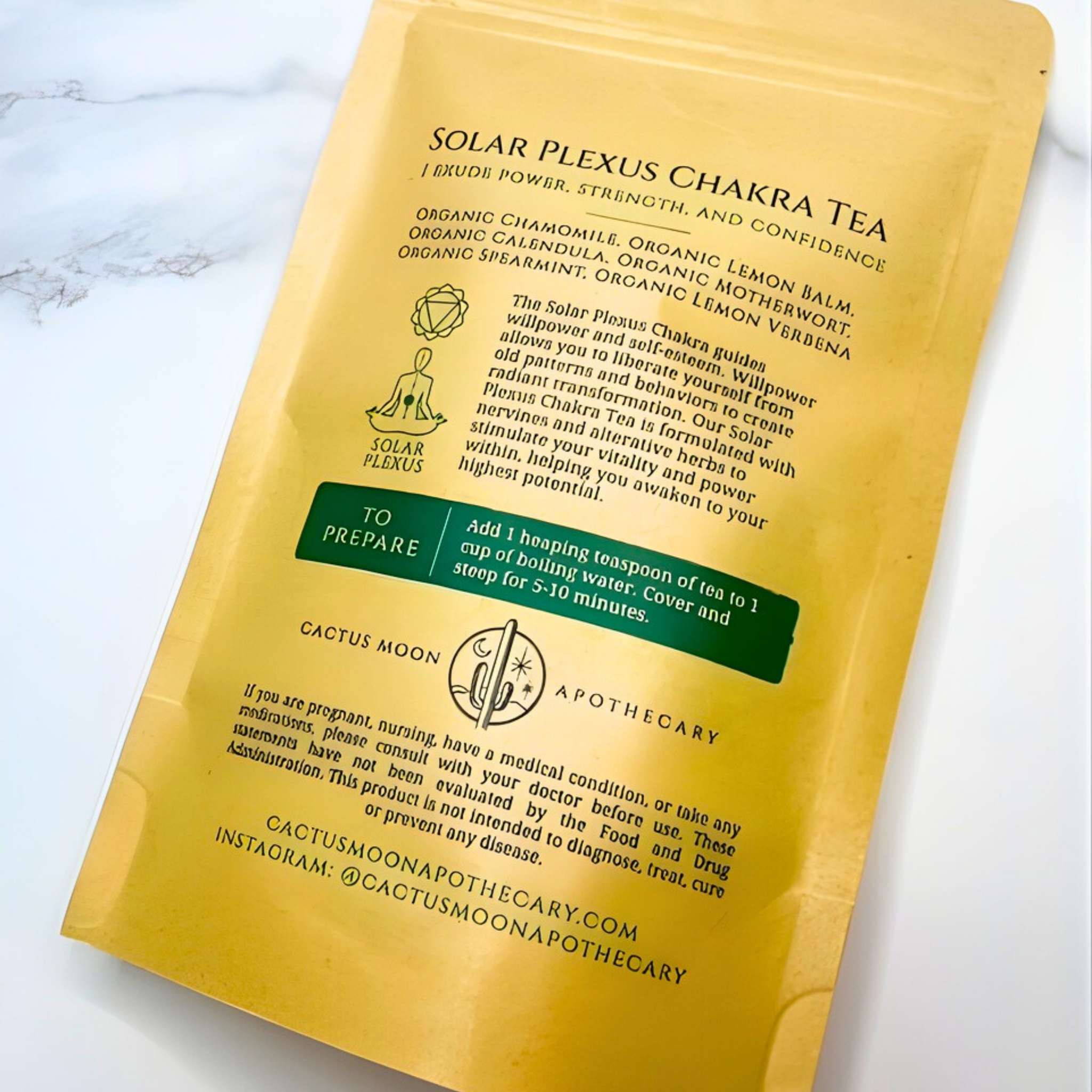 Yellow package of Solar Plexus Chakra Tea with text and branding on a white marble background