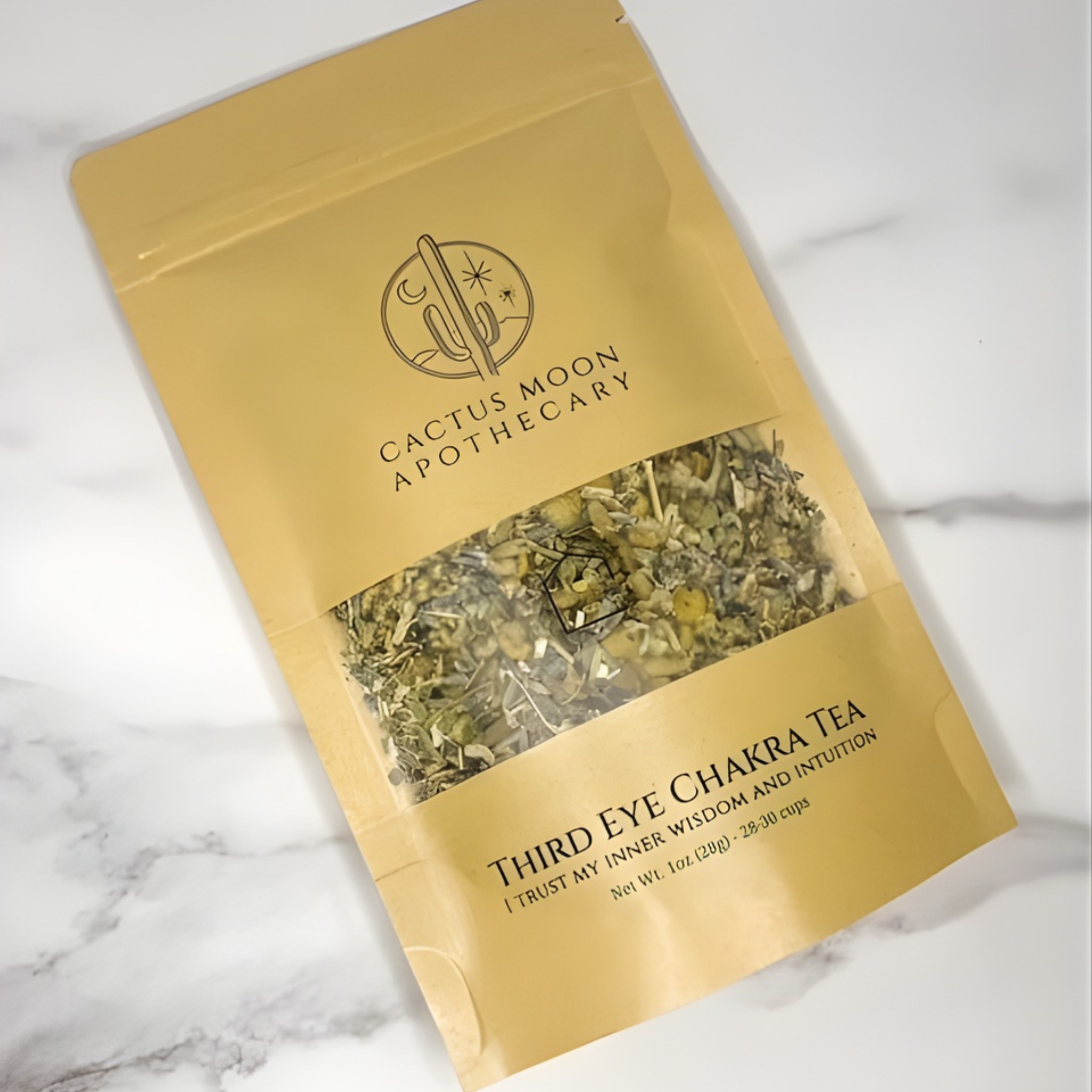 Gold packaging of Cactus Moon Apothecary Third Eye Chakra Tea on a marble surface