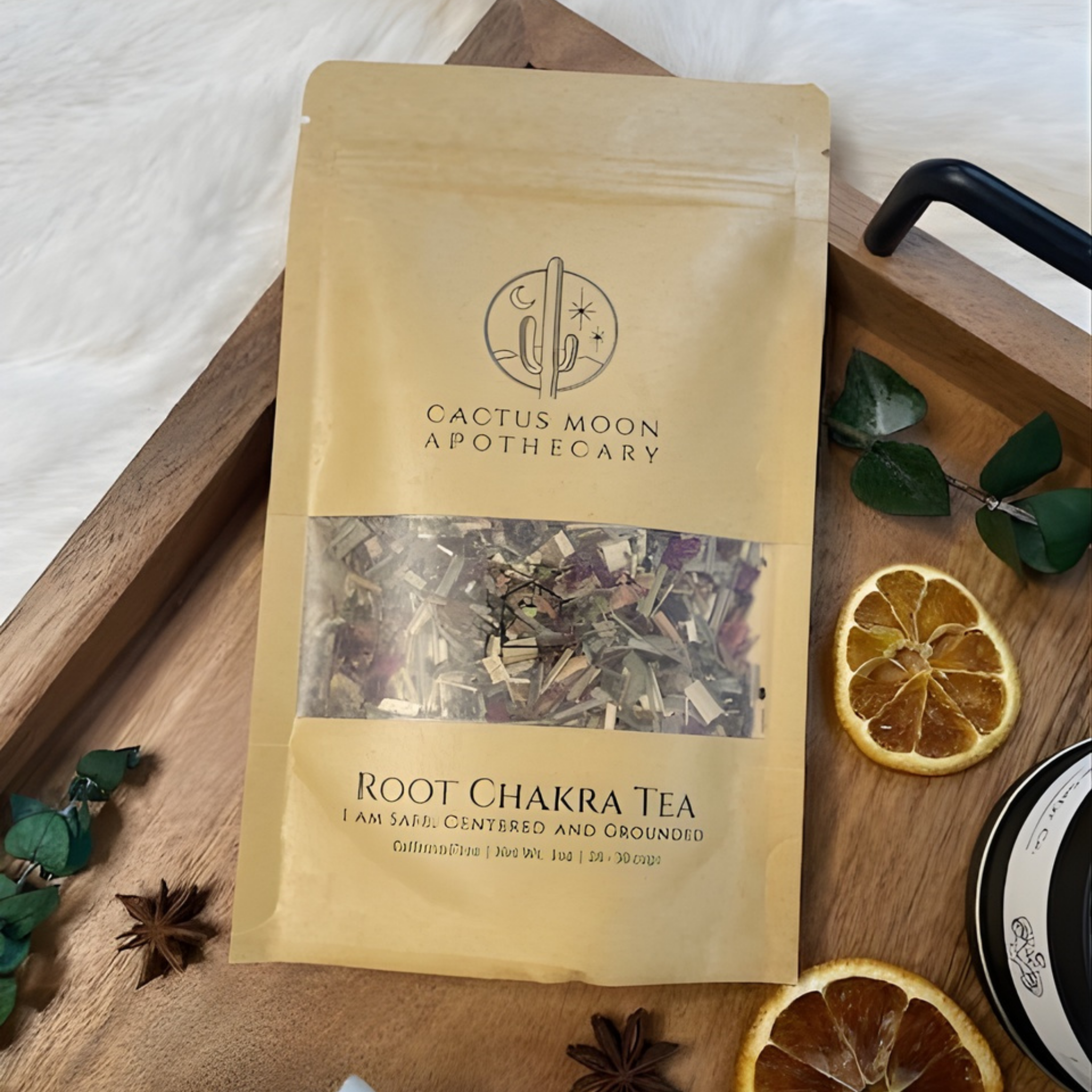 Cactus Moon Apothecary Root Chakra Tea package on a wooden tray with dried oranges and leaves.