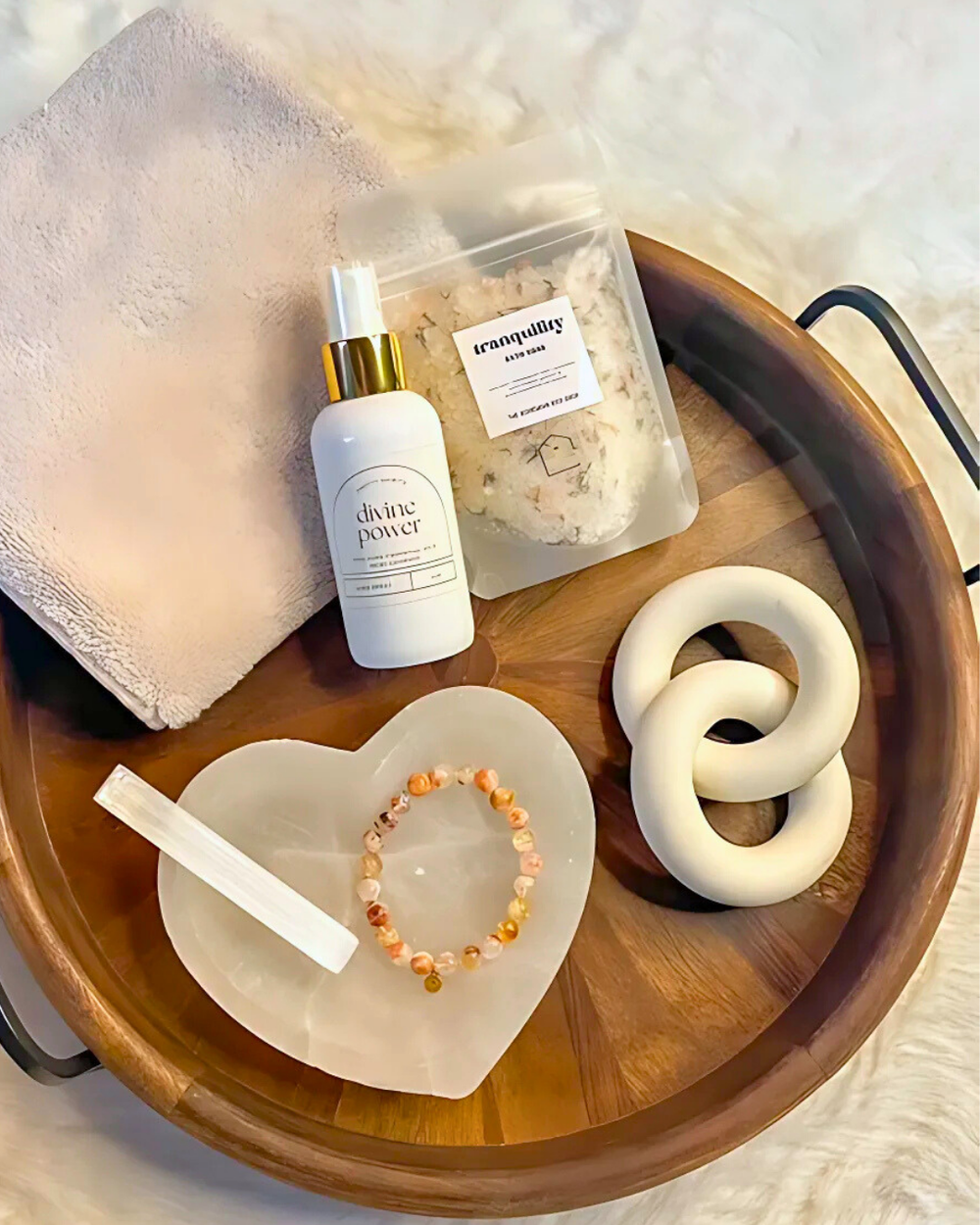 Wooden tray with a bottle, towel, and decorative items on a light background