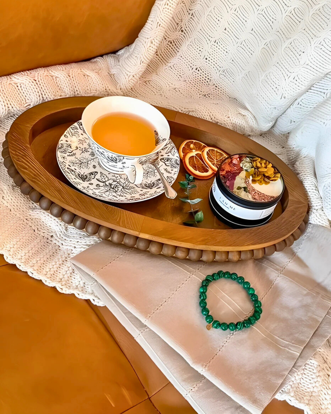 Tea cup and saucer on a wooden tray with decorative items, placed on a textured surface.