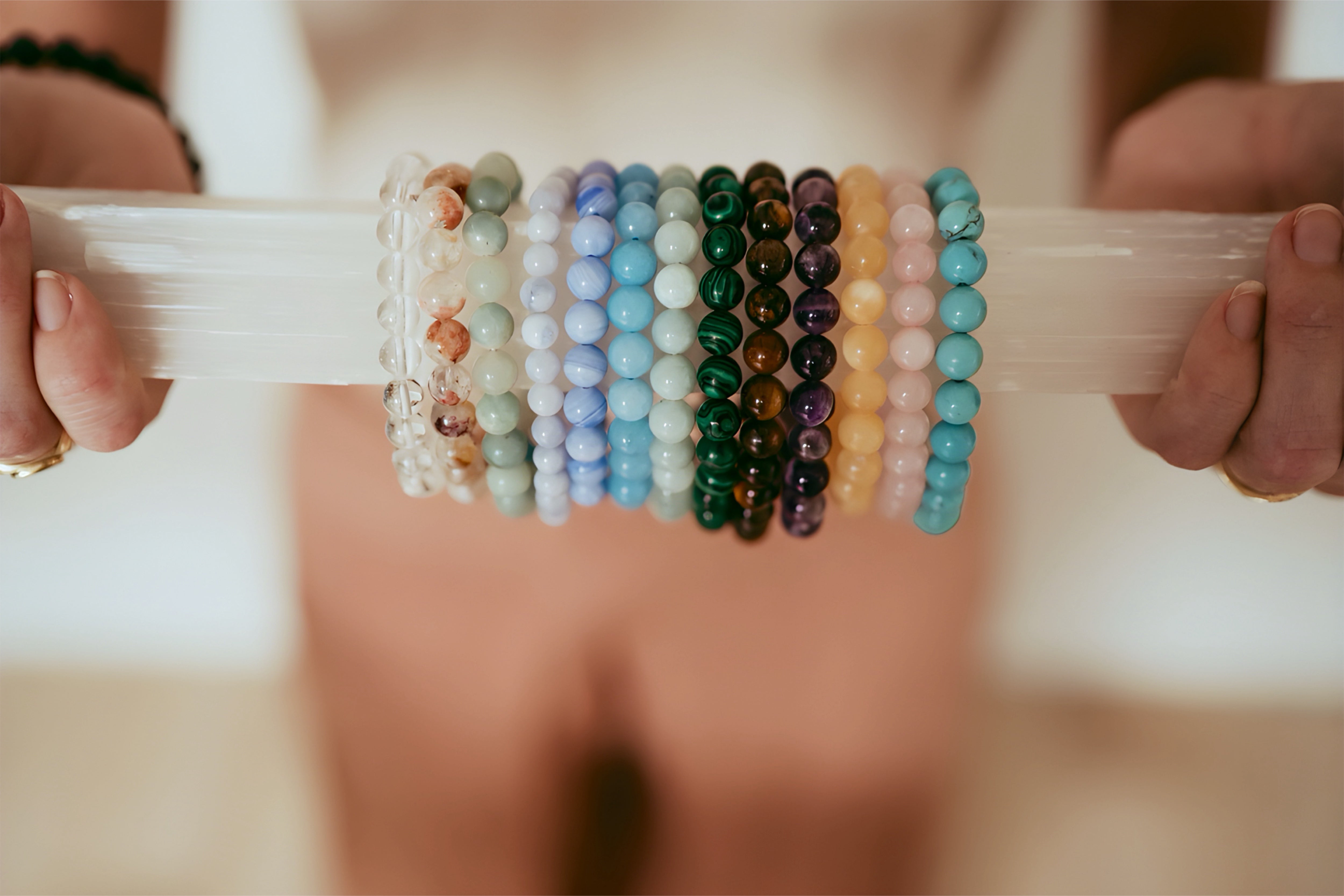 Colorful beaded bracelets on a stick held by hands against a blurred background
